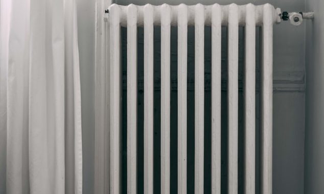 Old heater in a room next to a white curtain
